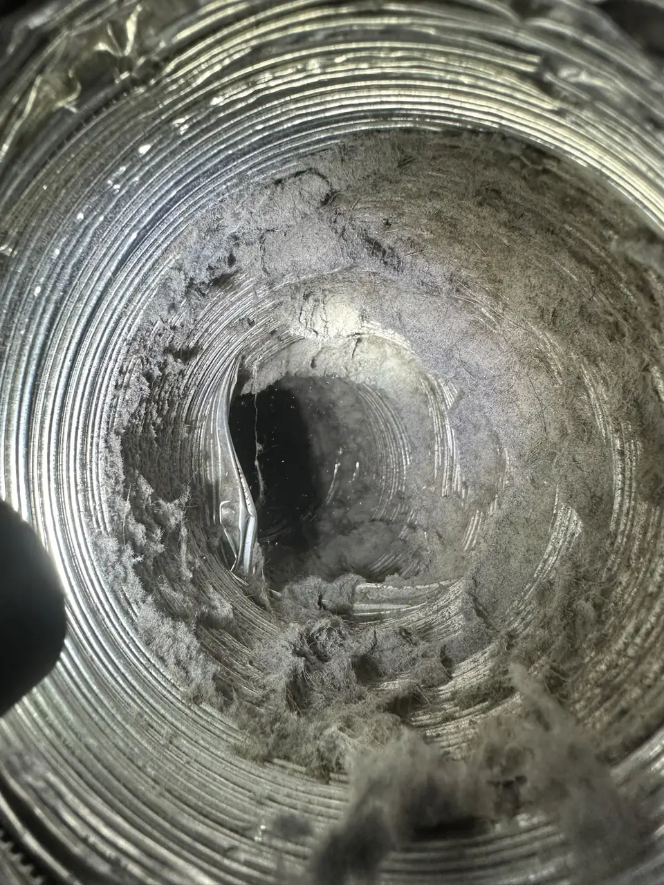 Flexible air duct coated in dust before cleaning